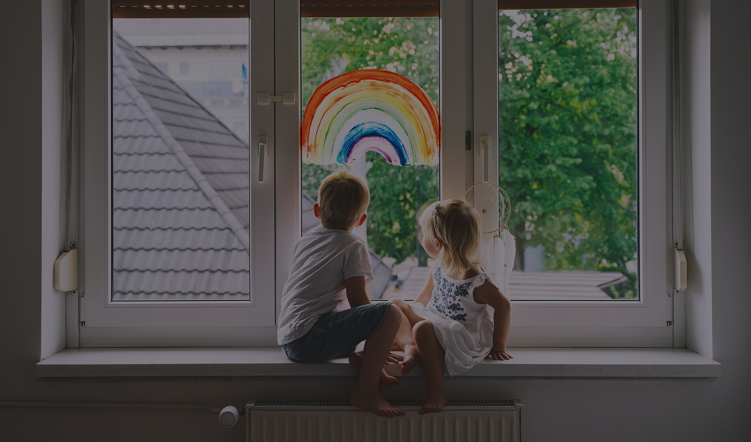 Children watching a rainbow through a window.