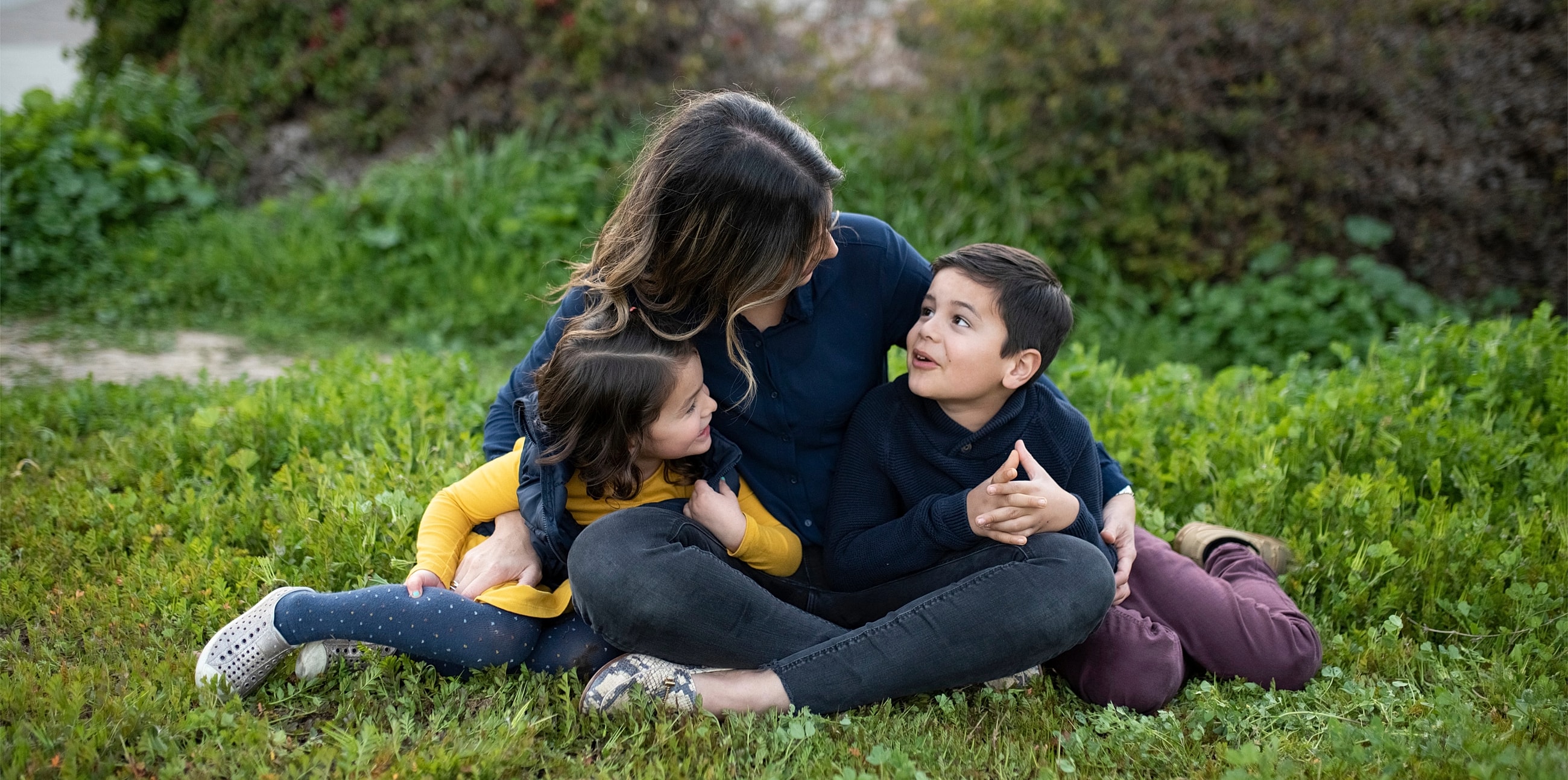 Woman and children sitting in grassy field.